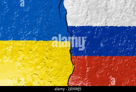 Die Flaggen der Ukraine und Russlands bemalten auf einer zerstörten Mauer und wurden durch einen Riss geteilt. Stockfoto