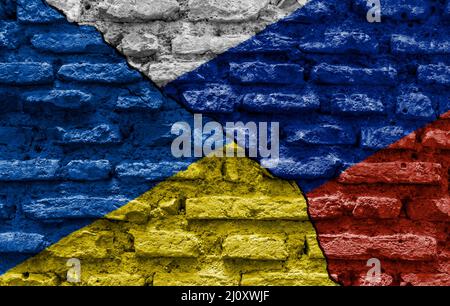 Die Flaggen der Ukraine und Russlands bemalten auf einer zerstörten Mauer und wurden durch einen diagonalen Riss geteilt. Stockfoto