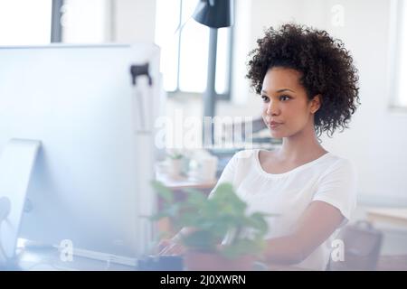 Moderne Frau für moderne Geschäftslösungen. Selbstbewusste Frau, die an ihrem Schreibtisch in einem offenen Bürobereich arbeitet. Stockfoto