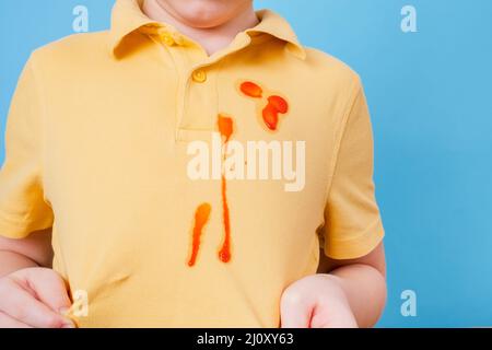 Nahaufnahme Fleck Tomatensauce verschüttet auf Kinder-Outfit. Das Konzept der Reinigung Flecken auf Kleidung Stockfoto