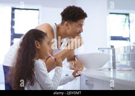 Biracial Tochter und Vater Zähneputzen zusammen im Bad zu Hause Stockfoto