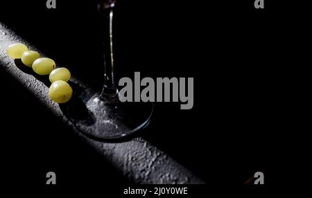 Trauben mit einem Glas Wein auf dunklem Hintergrund. Getränk Stockfoto