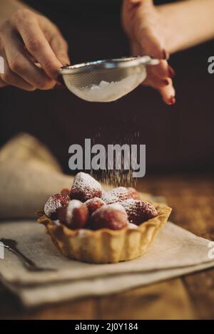 Frau staubt Zuckerpulver Erdbeerherbe Stockfoto