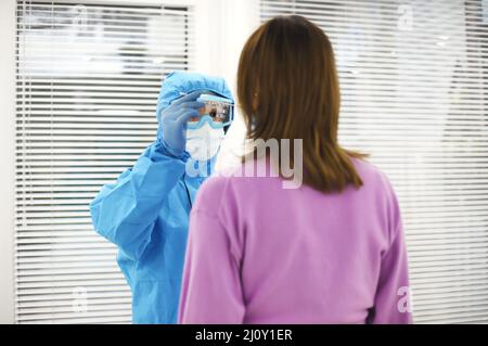 Krankenschwester in persönlicher Schutzausrüstung, die PCR-Test für Schwangeren macht und Nasenabstrich nimmt. Stockfoto