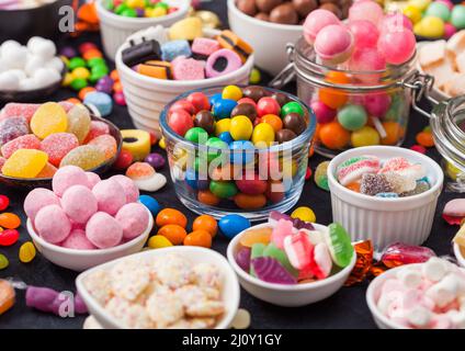 Auswahl an Milchschokolade und Gelee-Zucker-Gummibonbons und Bonbons auf Schwarz. Die besten Snacks für Kinderpartys. Stockfoto