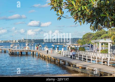 Die Menschen gehen um den Pier herum, der den Schwimmbereich am Balmoral Beach in Sydney, New South Wales, Australien, umgibt Stockfoto