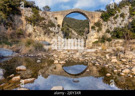 Blick auf eine alte Brücke Pont de Llierca in Katalonien, Spanien. Diese schöne Brücke, gepflastert mit Sandsteinplatten, ist seit dem 14.. Jahrhundert in Gebrauch. Stockfoto