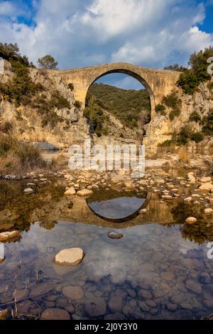 Blick auf eine alte Brücke Pont de Llierca in Katalonien, Spanien. Diese schöne Brücke, gepflastert mit Sandsteinplatten, ist seit dem 14.. Jahrhundert in Gebrauch. Stockfoto