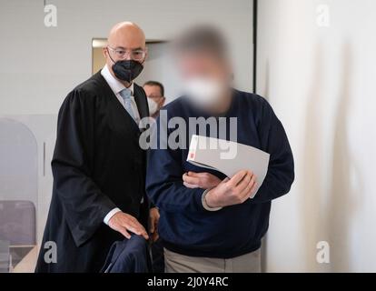 Bad Kreuznach, Deutschland. 21. März 2022. Der Angeklagte wird in Handschellen in den Gerichtssaal gebracht. Auf der linken Seite ist sein Anwalt Alexander Klein. Der Mann soll im vergangenen Jahr auf den Mitarbeiter einer Tankstelle in Bad Kreuznach geschossen haben, nachdem er ihm darauf hingewiesen hatte, dass er eine Coronamaske tragen müsse. Kredit: Boris Roessler/dpa - ACHTUNG: Der Angeklagte wurde durch Befehl des Gerichts/dpa/Alamy Live News pixeliert Stockfoto