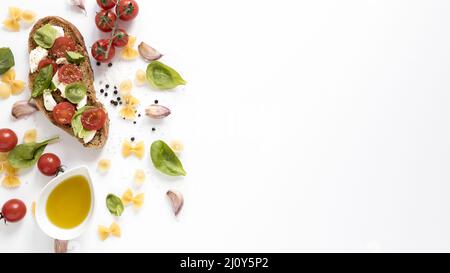 High-Angle-Ansicht Bruschetta farfalle rohe Pasta Knoblauchzehe Tomatenöl Basilikum Blatt vor isolierten weißen Hintergrund. Hohe Qualität Stockfoto