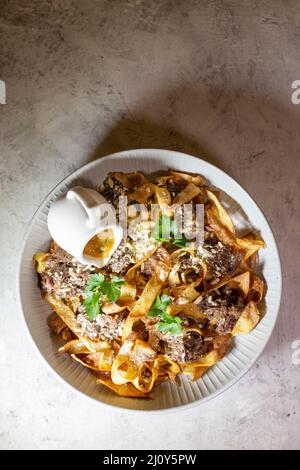 Gebratene Pasta mit Pferdefleisch auf einem weißen Teller Draufsicht Stockfoto