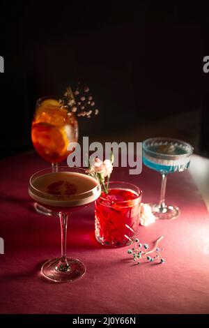Verschiedene Cocktails auf einem rosa Hintergrund im Dunkeln. Stockfoto