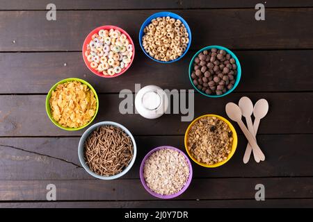 Direkt über einem Schuss verschiedener Frühstückszerealien, die in Schüsseln um die Milchflasche auf dem Tisch angeordnet wurden Stockfoto