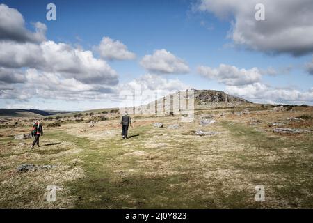 Wanderer, die auf dem rauen Bodmin Moor in Cornwall in Richtung Stowes Hill wandern.der Cheesewring. Stockfoto