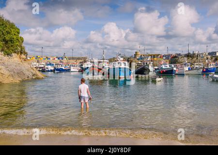 Ein Mann, der im Meer am historisch arbeitenden Newquay Harbour in Newquay in Cornwall steht. Stockfoto