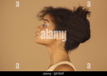 Profilansicht einer jungen, selbstbewussten afroamerikanischen Frau mit gesunder, klarer Haut und lockigen Haaren Stockfoto