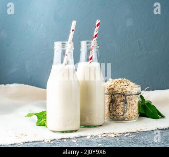 Smoothie mit Haferflocken, Minze für ein gesundes Frühstück. Hafermilch in Glasflasche mit Rohr auf dunklem Steingrund. Stockfoto