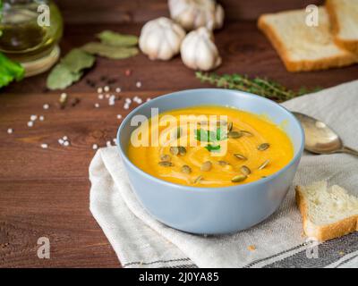 Vegetarische Ernährung pupmkin Creme Suppe pürieren, auf dunkelbraunen hölzernen Tisch, Seitenansicht, hautnah. Stockfoto