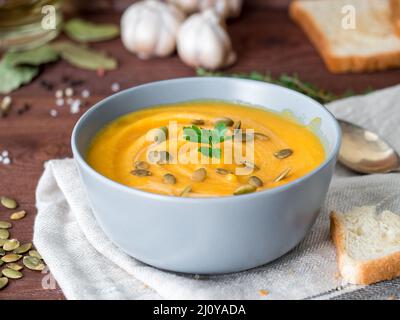 Vegetarische Ernährung pupmkin Creme Suppe pürieren, auf dunkelbraunen hölzernen Tisch, Seitenansicht, hautnah. Stockfoto
