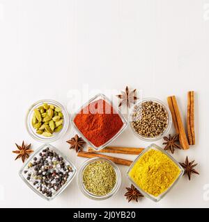 Gewürzset-Koriander, roter Pfeffer, Kurkuma, Zimt, Sternanise, Rosmarin verschiedene Gewürze in Glaspüssen, auf weißem Holztisch Stockfoto