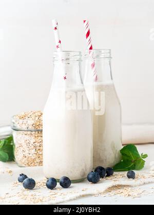 Smoothie mit Haferflocken, Minze für ein gesundes Frühstück. Hafermilch in Glasflasche mit Röhrchen auf weißem Hintergrund, selektiver Fokus. Stockfoto