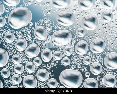 Abstrakte grauer Hintergrund mit großen und kleinen sphärischen konvexen Tropfen Wasser auf Glas. Blasen im Fenster". Makro Nahaufnahme. Stockfoto