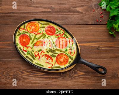 Bratpfanne mit Frittata in der Mitte auf einem braunen Holztisch, Draufsicht Stockfoto