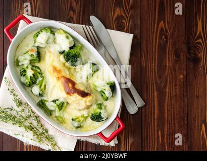 Hähnchenfilet mit Brokkoli in Bechamelsauce auf Holztisch gebacken. Gesunde Ernährung, saubere Ernährung Stockfoto
