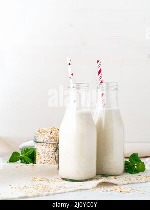 Smoothie mit Haferflocken, Minze für ein gesundes Frühstück. Hafermilch in Glasflasche mit Schlauch auf weißem Hintergrund. Stockfoto