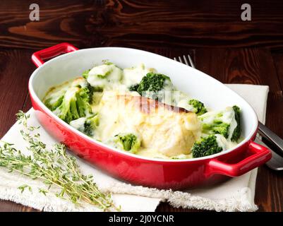 Hähnchenfilet mit Brokkoli in Bechamelsauce auf dunklem Holztisch gebacken. Gesunde Ernährung Stockfoto