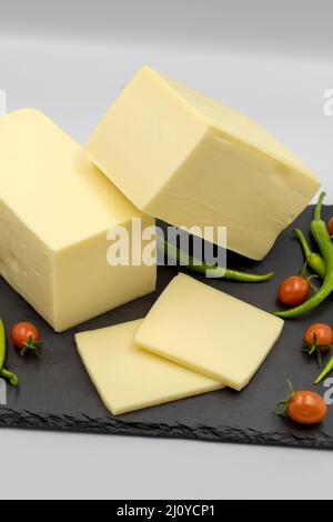 Cheddar-Käse oder Kashkaval-Käse auf weißem Hintergrund. Käsescheiben auf dem Servierbrett Stockfoto