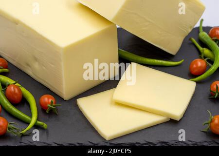 Cheddar-Käse oder Kashkaval-Käse auf weißem Hintergrund. Käsescheiben auf dem Servierbrett Stockfoto