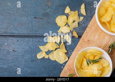 Direkt über dem Schuss Kartoffelchips in einer Schüssel mit Rosmarin auf dem Servierbrett am Holztisch Stockfoto