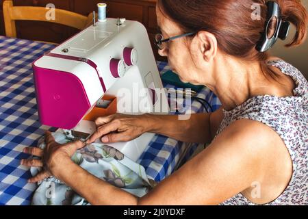 Frau mittleren Alters, die eine Nähmaschine benutzt, um ein Kleid zu machen Stockfoto