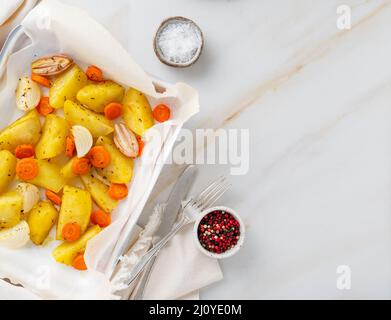 Bunt gebratenes Gemüse auf Tablett mit Pergament. Kartoffeln, Karotten und Zwiebeln. Stockfoto