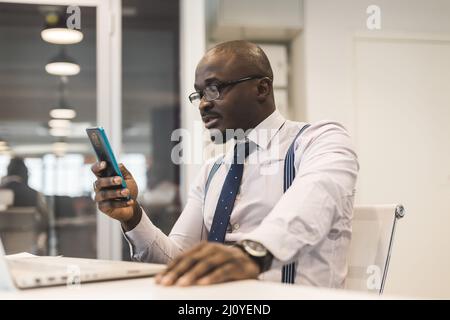 Porträt eines Afroamerikaners im Büro. Schwarzer Mann in einem Geschäftsanzug, der an einem Laptop arbeitet Stockfoto