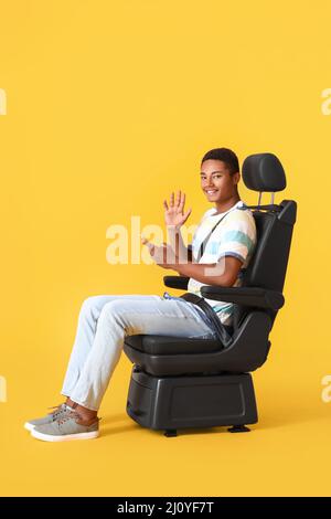 Afroamerikanischer Mann auf Autositz und mit Telefon auf farbigem Hintergrund Stockfoto