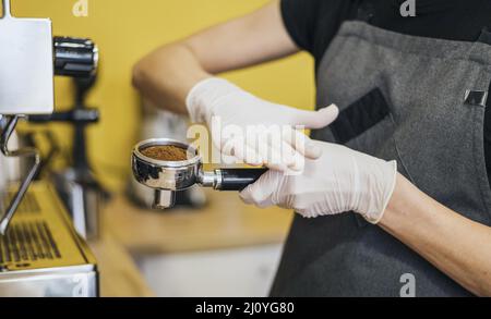 Seitenansicht Barista mit Latexhandschuhen zur Vorbereitung der Kaffeemaschine. Hochwertige Fotos Stockfoto