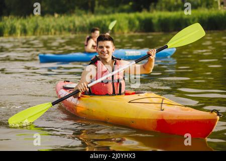 Lächelnder Mann, der mit dem Kajak auf dem See Hochwertige Fotos Stockfoto