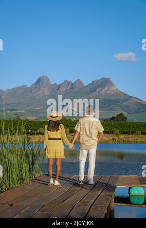 Ehepaar mit Blick auf den See, Weinberglandschaft bei Sonnenuntergang mit Bergen in Stellenbosch, in der Nähe von Kapstadt, South AF Stockfoto