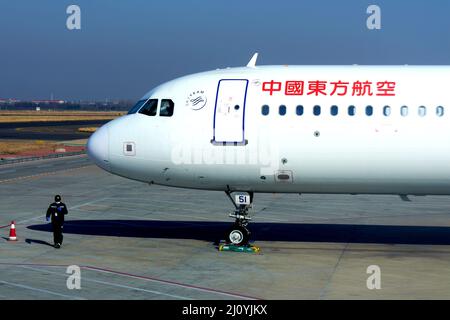 QINGDAO, CHINA - 21. FEBRUAR 2021 - ein Flughafenmitarbeiter fährt am Liuting Airpor vor einem angekohlten Passagierflugzeug der China Eastern Airlines Stockfoto