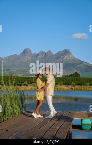 Ehepaar mit Blick auf den See, Weinberglandschaft bei Sonnenuntergang mit Bergen in Stellenbosch, in der Nähe von Kapstadt, South AF Stockfoto