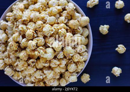 Overhead von Nahaufnahme von Karamell-Popcorn in einem Popcorn-Eimer. Beliebtes Essen für Film- oder Kinosnacks. Flach liegend. Unscharfer Hintergrund. Stockfoto