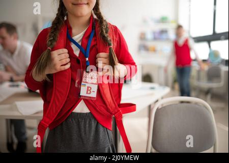 Schulmädchen mit Blutbild Aufkleber in der Schule, ukrainische Kriegskonzept. Stockfoto