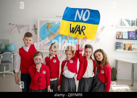 Kleine Schüler machen Urlaub und zeigen ukrainische Flagge im Klassenzimmer, kein Kriegskonzept. Stockfoto