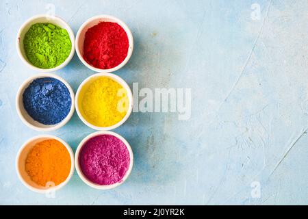 Bunte holi Farbe Pulver in weißen Schalen gemalt blauen Hintergrund. Hochwertige Fotos Stockfoto