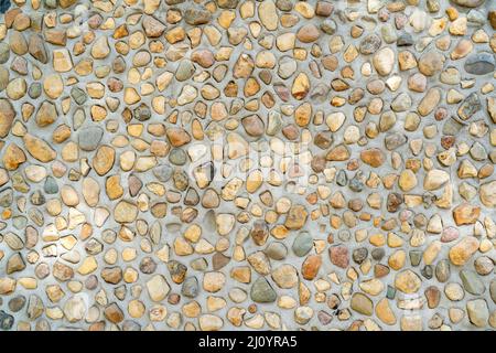 Steine in Beton. Grau Textur von unebenen Putz auf der Wand des Hauses. Stockfoto