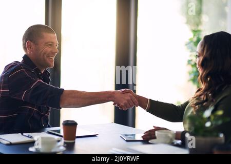 Es ist ein Vergnügen, Geschäfte mit Ihnen zu machen. Aufnahme von zwei fröhlichen Geschäftsleuten, die sich nach einem Treffen in einem Sitzungssaal einverstaffelt haben. Stockfoto