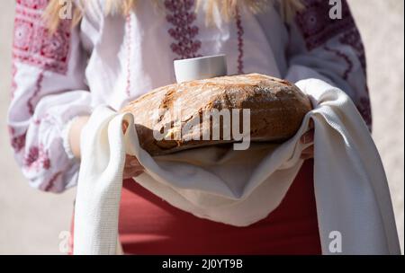 München, Deutschland. 21. März 2022. Eine Studentin in ukrainischer Tracht steht vor der Ukrainischen Freien Universität (UFU) und hält Brot und Salz in den Händen zum Gruß. Der Wissenschaftsminister von Bayern, Blume (CSU), besucht die UFU. Die UFU ist die einzige ukrainische Universität im Exil außerhalb der Ukraine. Quelle: Sven Hoppe/dpa/Alamy Live News Stockfoto