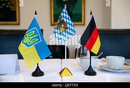 München, Deutschland. 21. März 2022. Die Flaggen der Ukraine, Bayerns und Deutschlands stehen auf einem Tisch in der Freien Ukrainischen Universität München (UFU). Der Wissenschaftsminister von Bayern, Blume (CSU), hat die (UFU) besucht. Die UFU ist die einzige ukrainische Universität im Exil außerhalb der Ukraine. Quelle: Sven Hoppe/dpa/Alamy Live News Stockfoto